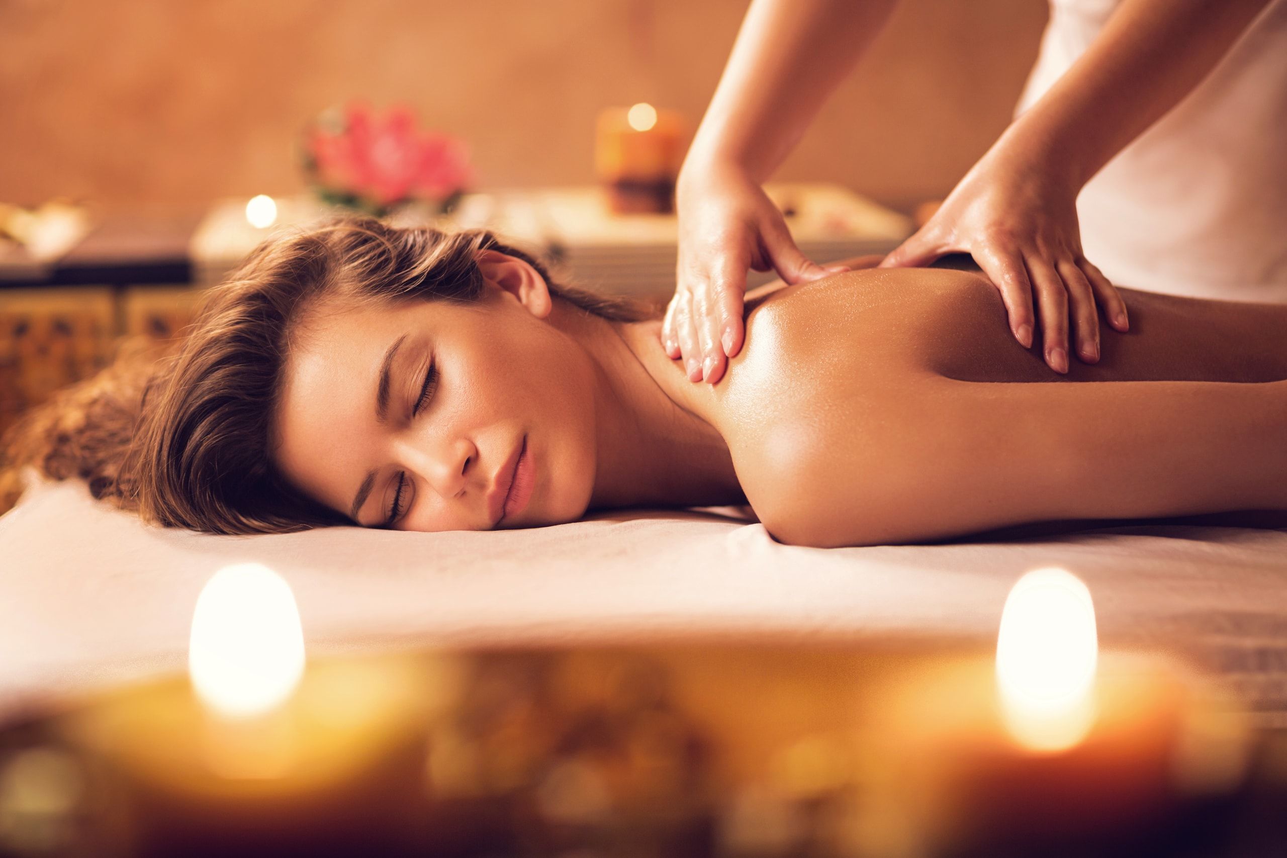Entspannte Frau bei einer Rückenmassage im Kerzenlicht